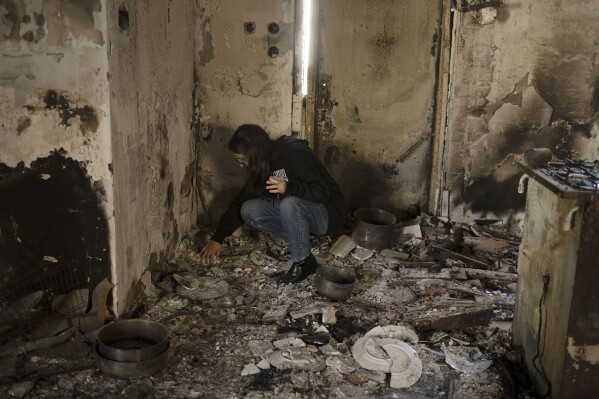 Sharon Alony Cunio searches for a necklace on Monday, Jan. 15, 2024, in what remains of her kitchen in Kibbutz Nir Oz, from where she was kidnapped with her family on Oct. 7, 2023, by Hamas. Cunio and her twin daughters were freed in November, but her husband remains in captivity in Gaza. (AP Photo/Maya Alleruzzo)