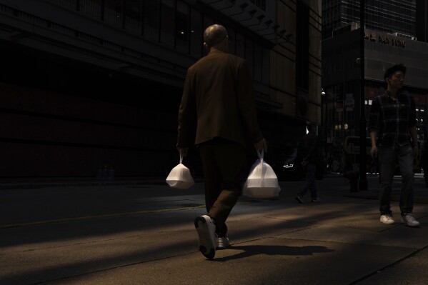 A pedestrian carries takeaway food plastic bags in Hong Kong, Wednesday, March 13, 2024. Hong Kong has long been a major producer and consumer of great food, and a great amount of plastic and Styrofoam to go with it. That’s going to change as new legislation aiming to stop the sale and distribution of Styrofoam products and single-use plastic cutlery went into effect on Monday, April 22, 2024.(AP Photo/Louise Delmotte)