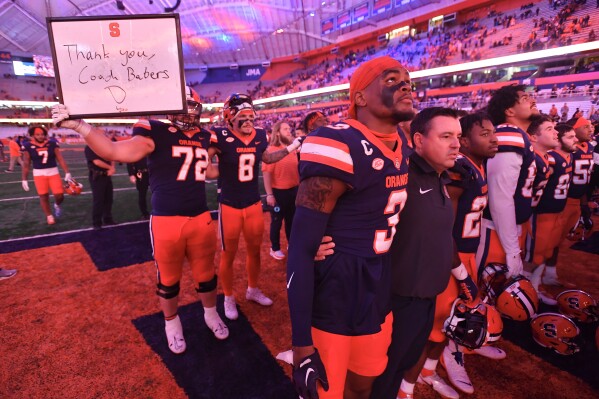 Syracuse interim head coach Nunzio Campanile, second from front left, stands with defensive back Isaiah Johnson, front left, offensive lineman Mark Petrie (72) with former coach Dino Babers after their win over Wake Forest in an NCAA college football game Keep a sign for.  In Syracuse, NY, Saturday, November 25, 2023.  Campanile replaced Babers, who was fired earlier in the week.  (AP Photo/Adrian Cross)