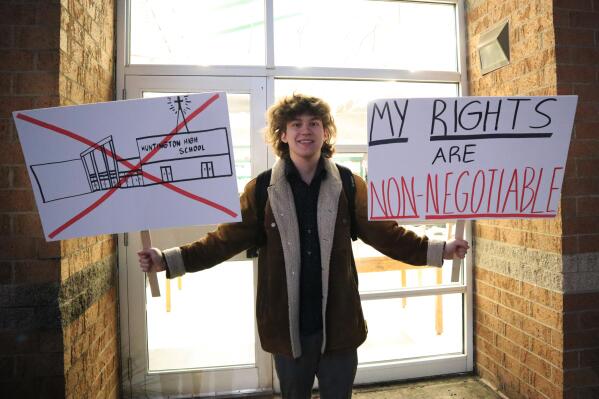 Huntington High School senior Max Nibert holds signs he plans to use during a student walkout at the school in Huntington, W.Va. on Wednesday, Feb. 9, 2022. The protest follows an evangelistic Christian revival assembly last week that some students at Huntington High were mandated by teachers to attend – a violation of students’ civil rights, Nibert says. (AP Photo/Leah M. Willingham)