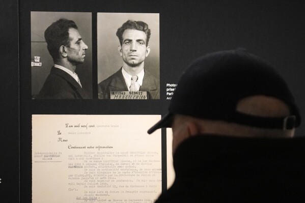 A visitor watches the Nov.18, 1943 police mugshot of Missak Manouchian, exhibited at the Shoah memorial, Tuesday, Feb. 20, 2024 in Paris. Missak Manouchian will enter into the Pantheon national monument Wednesday during a ceremony presided by French President Emmanuel Macron. Manouchian, who took refuge in France after surviving the Armenian genocide, was executed in 1944 for fighting fascism and leading resistance to Nazi occupation. The Pantheon is the final resting place of France's most revered figures. (AP Photo/Michel Euler)