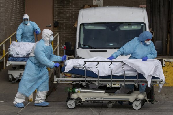 Medical personnel wearing personal protective equipment remove bodies from the Wyckoff Heights Medical Center Thursday, April 2, 2020 in the Brooklyn borough of New York.  As coronavirus hot spots and death tolls flared around the U.S., the nation's biggest city was the hardest hit of the all, with bodies loaded onto refrigerated morgue trucks by gurney and forklift outside overwhelmed hospitals, in full view of passing motorists.   (AP Photo/Mary Altaffer)