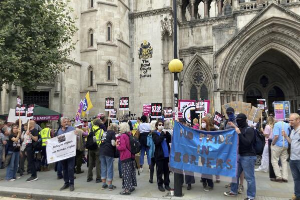 Demonstrators stand outside the Royal Courts of Justice, protesting against the government's plan to send some asylum seekers to Rwanda, while a High Court hearing over the policy is ongoing, in London, Monday,  Sept. 5, 2022. The British government’s plan to give some asylum-seekers a one-way ticket to Rwanda faces a legal challenge in the High Court on Monday. Immigrant-rights groups argue that the policy is both illegal and immoral.  (Sian Harrison/PA via AP)