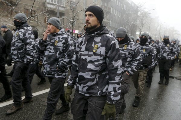 
              Volunteers with the right-wing paramilitary Azov National Corps during a rally on the snowy streets in front of the Ukrainian parliament in Kiev, Ukraine, Monday, Nov. 26, 2018. Some hundreds of protesters from far-right party National Corps brandished yellow-and-blue flags with the Ukrainian national trident symbol, and a banner reading 'Don't back down!" (AP Photo/Efrem Lukatsky)
            