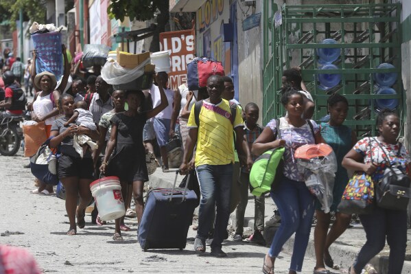 FILE - Residents flee their homes to escape clashes between armed gangs in the Carrefour-Feuilles district of Port-au-Prince, Haiti, Aug. 15, 2023. Kenya’s government said Nov. 9, 2023 that its police will not be deployed to Haiti until all conditions on training and funding are met in line with last month’s approval from the U.N Security Council to give the eastern African country command of a multinational mission to combat violent gangs in Haiti. (AP Photo/Odelyn Joseph, File)