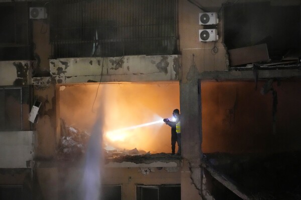 Civil defense workers search for survivors inside an apartment following a massive explosion in the southern suburb of Beirut, Lebanon, Tuesday, Jan. 2, 2024. The TV station of Lebanon's Hezbollah group says top Hamas official Saleh Arouri was killed Tuesday in an explosion in a southern Beirut suburb.(AP Photo/Hussein Malla)