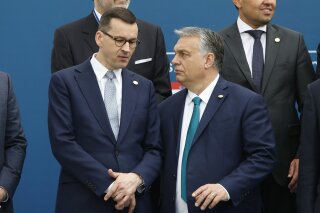 FILE - In this Feb. 1, 2020 file photo, Poland's Prime Minister Mateusz Morawiecki, left, and Hungary's Prime Minister Victor Orban share a word as they line up for a group picture prior to a meeting in Beja, Portugal. Polish government officials insisted on Friday, Dec. 4, 2020, that they are sticking to their tough negotiating position ahead of a key European Union summit next week that should finalize the bloc’s next seven-year budget and a major pandemic recovery package. (AP Photo/Armando Franca, File)