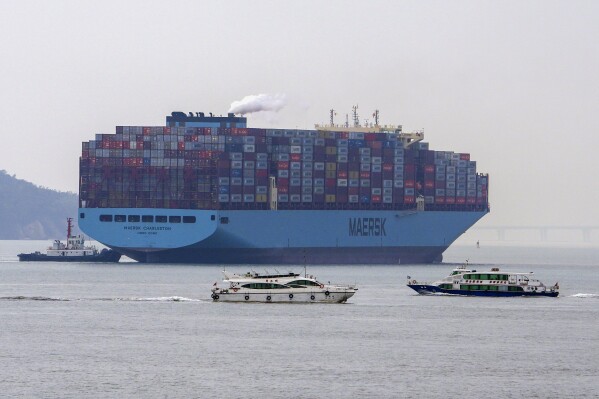 Ferries sail by a containers vessel prepares to dock at a port in Xiamen in southeast China's Fujian province on Dec. 27, 2023. China's exports grew slightly for a second consecutive month in December even as deflationary pressures continue, according to official data released Friday, Jan. 12, 2024 underscoring an uneven recovery in 2023. (AP Photo/Andy Wong)