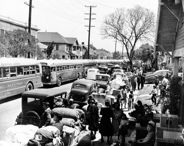This 1942 photo shows the evacuation of American-born Japanese civilians during World War II, as they leave their homes for internment, in Los Angeles, California. The sidewalks are piled high with indispensable personal possessions, cars and buses are waiting to transport the evacuees to the war relocation camps. (AP Photo)