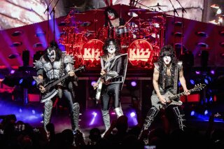 File, in this Aug. 29, 2019 file photo, KISS performs at the the Riverbend Music Center in Cincinnati. In front from left are Gene Simmons, Tommy Thayer and Paul Stanley. Eric Singer is in the back on drums. The rock group will play a Nov. 2019 show in Australia for sharks and eight fans in a small submarine. They will listen through underwater speakers as the band remains above board on a boat.(Photo by Amy Harris/Invision/AP, File)