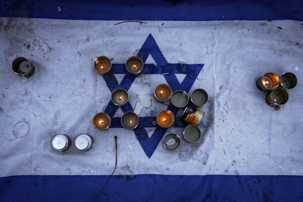 Candles are placed on an Israeli flag at a vigil for the victims of the bloody Oct. 7 cross-border attack by Hamas militants, in which at least 1,200 people were killed and 240 people kidnapped, mostly Israeli citizens, in central Tel Aviv, Israel, Friday, Nov. 10, 2023. (AP Photo/Oded Balilty)