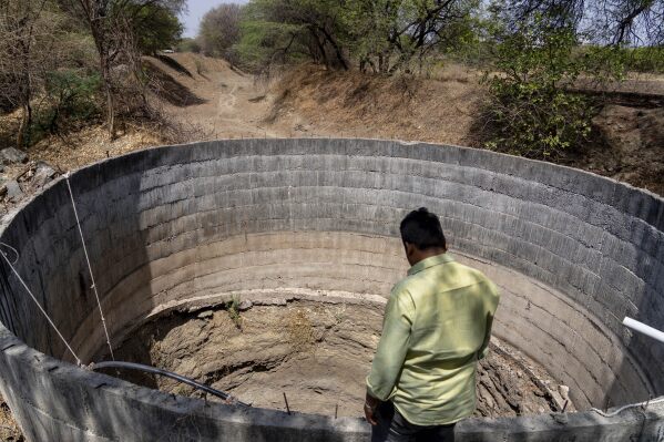 A farmer looks down into a dry well due to drought outside Beed, India, Friday, May 3, 2024. Voters in India, from the rain-drenched Himalayas in the north to the sweltering, dry south, are looking for politicians who promise relief, stability and resilience to the wide-ranging and damaging effects of a warming climate. But experts and voters say there has been little talk about climate change on the campaign trail. (AP Photo/Rafiq Maqbool)