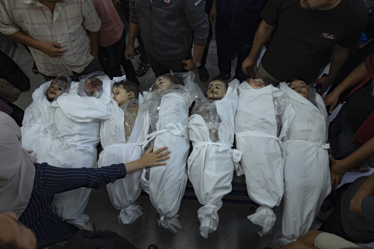 EDS NOTE: GRAPHIC CONTENT - Palestinians stand around the bodies of children killed in the Israeli bombardment of the Gaza Strip in a morgue in Khan Younis, Thursday, Oct. 19, 2023. (AP Photo/Fatima Shbair)