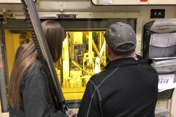 FILE - In this Nov. 29, 2018 photo, hot cell operators Dawnette Hunter, left, and Scot White manipulate radioactive material from behind 4-foot-thick leaded glass at the Hot Fuel Examination Facility at the Idaho National Laboratory about 50 miles west of Idaho Falls, Idaho. The U.S. Department of Energy has selected Idaho as the site for a proposed nuclear test reactor that would dramatically reduce the time needed to develop nuclear fuels and components for a new generation of nuclear reactors. The Energy Department on Wednesday, July 27, 2022, said it selected its 890-square-mile site in eastern Idaho that includes the Idaho National Laboratory to build the Versatile Test Reactor, or VTR. (AP Photo/Keith Riddler,File)