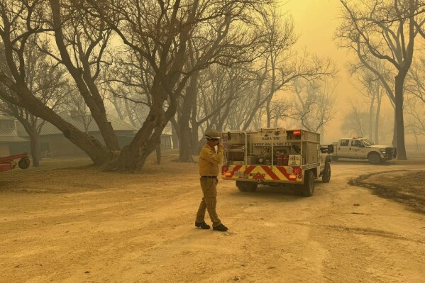 In this photo provided by the Flower Mound, Texas Fire Department, Flower Mound firefighters respond to a fire in the Texas Panhandle on Tuesday, February 27, 2024. A rapidly growing wildfire in Texas doubled in size on Tuesday, prompting evacuation orders for at least a year. A small town.  (Flower Mound Fire Department via AP)