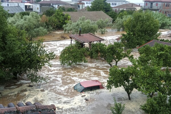 Floodwaters cover a car and the yards of houses in Milina village, Pilion region, central Greece, Tuesday, Sept. 5, 2023. Greek police have ordered vehicles off the streets of the central town of Volos and the nearby mountain region of Pilion as a severe storm has hit the area, turning streets into flooded torrents. (Thanasis Kalliaras/Eurokinissi via AP)
