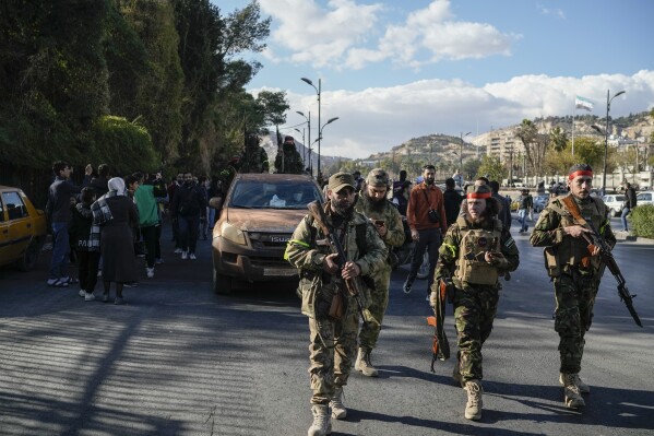 Syrian fighters walk to attend a celebratory demonstration following the first Friday prayers since Bashar Assad's ouster, in Damascus' central square, Syria, Friday, Dec. 13, 2024. (AP Photo/Leo Correa, File)
