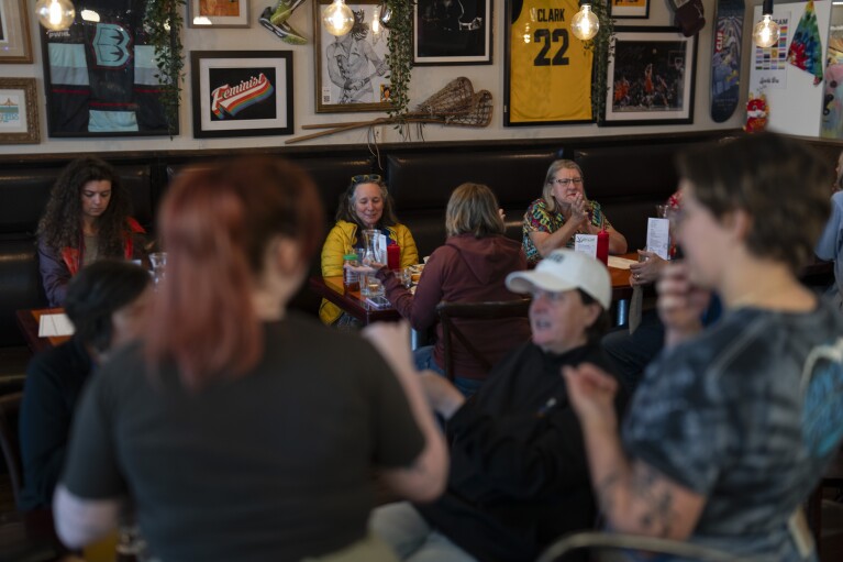 As a Caitlin Clark jersey is displayed in the background, customers eat and watch college women's lacrosse and beach volleyball matches at The Sports Bra sports bar on Wednesday, April 24, 2024, in Portland, Ore. (AP Photo/Jenny Kane)