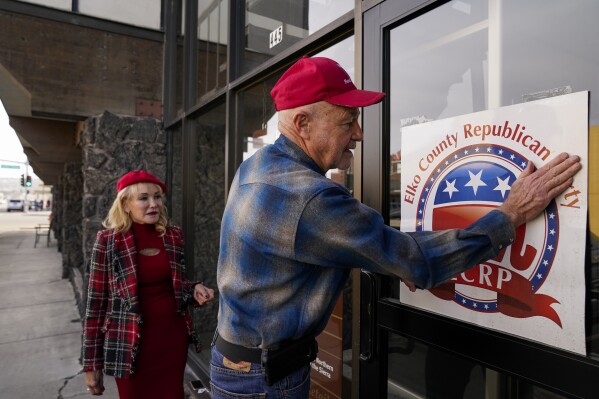 Lee Hoffman, derecha, pega un letrero del Partido Republicano en el condado Elko en la ventana de una construcción propiedad de Lina Blohm, izquierda, el sábado 16 de diciembre de 2023, en Elko, Nevada. (AP Foto/Godofredo A. Vásquez)