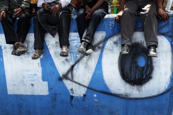 FILE - In this Nov. 17, 2019 file photo, supporters of former President Evo Morales sit over a mural emblazoned with his first name, in Sacaba, Bolivia. Morales, a 60-year-old former coca farmer and union leader, faces terrorism and other charges in Bolivia and is not an election candidate in the upcoming October elections. Some human rights advocates believe the charges amount to political persecution of Morales. (AP Photo/Juan Karita, File)