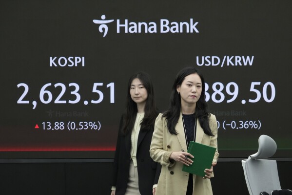 Currency traders pass by the screen showing the Korea Composite Stock Price Index (KOSPI), left, and the foreign exchange rate between U.S. dollar and South Korean won at the foreign exchange dealing room of the KEB Hana Bank headquarters in Seoul, South Korea, Wednesday, April 17, 2024. (AP Photo/Ahn Young-joon)