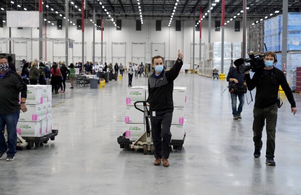 A worker gives a thumbs up while transporting boxes containing the Moderna COVID-19 vaccine to the loading dock for shipping at the McKesson distribution center in Olive Branch, Miss., Sunday, Dec. 20, 2020. (AP Photo/Paul Sancya, Pool)