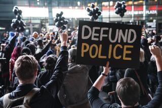 FILE - In this Oct. 14, 2020, file photo a protester holds a sign that reads "Defund Police" during a rally for the late George Floyd outside Barclays Center in New York. Some police organizations and Republican politicians are blaming Democrats and last year's defund the police effort for a troubling rise in homicides in many cities across the country. The increases are real, and some cities did make modest cuts to police spending. But the claims by Republicans overlook the fact homicides are up in many cities, including ones that increased police spending or have Republican mayors. (AP Photo/John Minchillo, File)