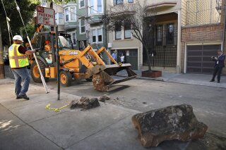 In this Monday, Sept. 30, 2019, photo, a San Francisco Public Works crew removes boulders from a sidewalk along a street in San Francisco, Monday, Sept. 30, 2019. A group of San Francisco neighbors say they bought boulders and had them delivered to their sidewalk to stop people from camping and dealing drugs on their street. (Liz Hafalia/San Francisco Chronicle via AP)