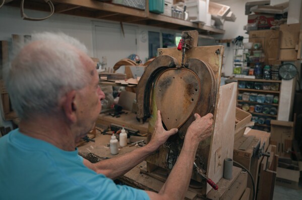 Mike Dulak bends a piece of wood to shape the frame of a mandolin, in his workshop in Rocheport, Mo., Friday, Sept. 8, 2023.  (AP Photo/Jessie Wardarski)