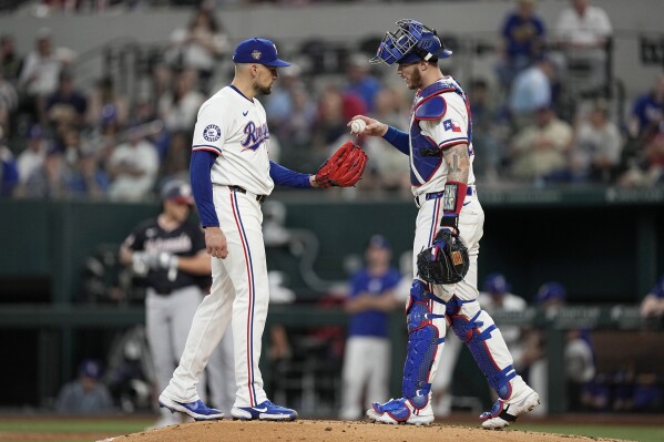 Texas Rangers' Nathan Eovaldi, left, and catcher Jonah Heim talk on the mound during the third inning of a baseball game against the Washington Nationals in Arlington, Texas, Thursday, May 2, 2024. (AP Photo/Tony Gutierrez)