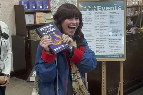 Ella Dolynchuk holds her copy of "Sunrise on the Reaping" by Suzanne Collins at a midnight launch party at Barnes & Noble bookstore in New York on Tuesday, March 18, 2025. (AP Photo/Hillel Italie)
