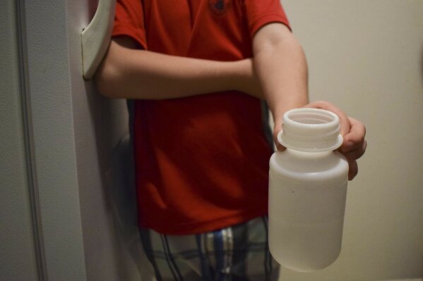 Leona Peterson's son, Wayne, 6, holds his water bottle filled from a freestanding water cooler at his home in Prince Rupert, British Columbia, Canada on July 19, 2019. He knows about the presence of lead in the tap water, and drinks purified water instead. (Mackenzie Lad/Institute for Investigative Journalism/Concordia University via AP)