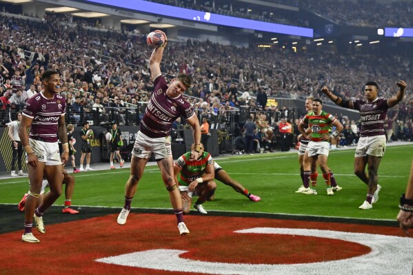 Sea Eagles Reuben Garrick, centre, celebrates after scoring a try during the opening match of the NRL between the Manly Warringah Sea Eagles and the South Sydney Rabbitohs at Allegiant Stadium in Las Vegas, Saturday, March 2, 2024. (AP Photo/David Becker)