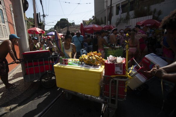 Vendors push Styrofoam coolers through a crowd of revelers at the Heaven on Earth pre-Carnival street party, in Rio de Janeiro, Saturday, Feb. 22, 2025. (AP Photo/Bruna Prado)