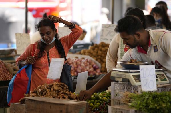 FILE - A woman bargains as she buys vegetables at a market place in Colombo, Sri Lanka, Friday, June 10, 2022. The International Monetary Fund said Thursday, Sept. 1, 2022, it has reached a staff-level agreement with Sri Lanka to provide $ 2.9 billion over four years to help salvage the country from its worst economic crisis in recent memory. (AP Photo/Eranga Jayawardena, File)
