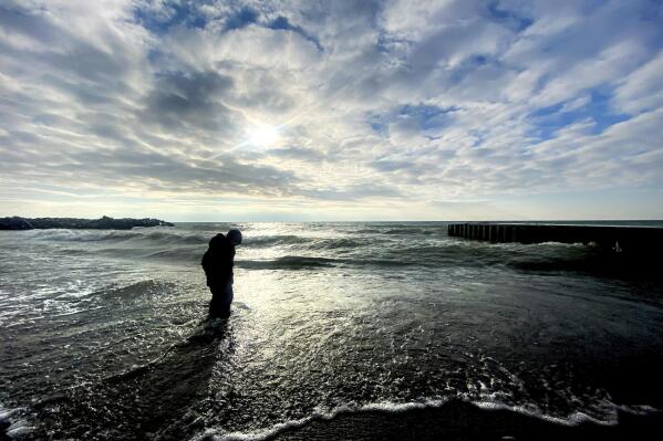FILE - A young boy plays in the surf by the shore of Lake Ontario in Toronto on Jan. 21, 2021. Studies predict the Great Lakes and other large freshwater bodies around the world will move toward acidity as they absorb excess carbon dioxide from the atmosphere, which also causes climate change. Experts say acidification could disrupt aquatic food chains and habitat. (Frank Gunn/The Canadian Press via AP, File)