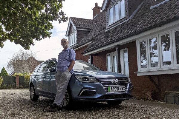John Kirkwood poses for a selfie with his car near Paston, Norfolk, England, Wednesday, Sept. 27, 2023. Chinese automakers are winning over drivers as they make major inroads into Europe’s electric vehicle market, challenging long-established homegrown brands in an industry that’s key to the continent’s green energy transition. The European Union has launched an investigation into Beijing’s support for its EV industry, adding to tensions between the West and China.(John Kirkwood via AP)