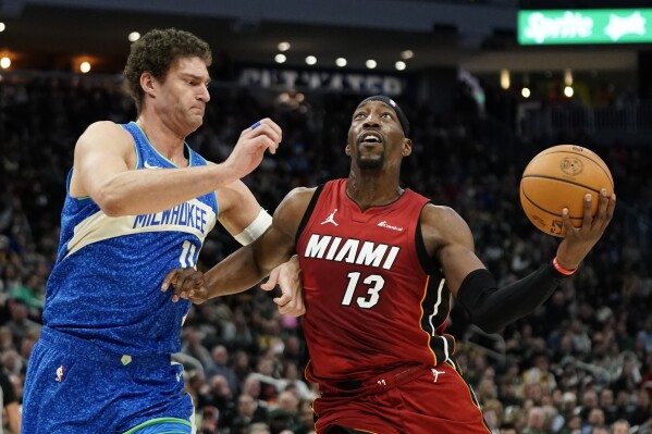 Miami Heat's Bam Adebayo (13) drives to the basket against Milwaukee Bucks' Brook Lopez during the first half of an NBA basketball game, Tuesday, Feb. 13, 2024, in Milwaukee. (AP Photo/Aaron Gash)