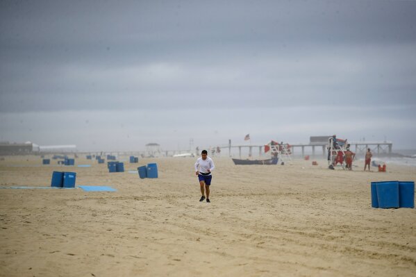 A runner passes along a mostly empty beach, Saturday, May 23, 2020, in Belmar, N.J. (AP Photo/John Minchillo)