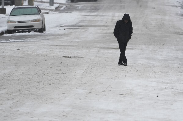 A person crosses a snow covered street Thursday, Jan. 18, 2024, in Nashville, Tenn. A snowstorm blanketed the area with up to eight inches of snow and frigid temperatures.(AP Photo/George Walker IV)