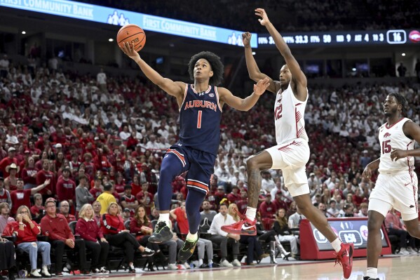 Auburn guard Aden Holloway (1) drives past Arkansas guard Tramon Mark (12) on a fast break during the first half of an NCAA college basketball game Saturday, Jan. 6, 2024, in Fayetteville, Ark. (AP Photo/Michael Woods)