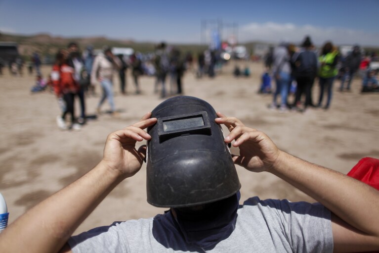 FILE - Using a welder's mask as protection, a man views a total eclipse in Piedra del Aguila, Argentina, Monday, Dec. 14, 2020. The total solar eclipse was visible from the northern Patagonia region of Argentina and from Araucania in Chile, and as a partial eclipse from the lower two-thirds of South America. (AP Photo/Natacha Pisarenko, File)