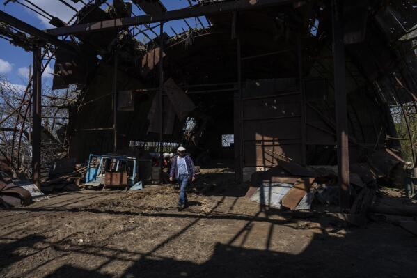 Ukrainian farmer Oleh Uskhalo walks inside a destroyed warehouse in Potomkyne, Kherson region, Ukraine, Tuesday, April 25, 2023. Bankruptcy is looming for many Ukrainian farmers across the war-torn country who are struggling to seed crops amid widespread mine contamination in areas once occupied by Russian forces and rising costs associated with exports. (AP Photo/Bernat Armangue)