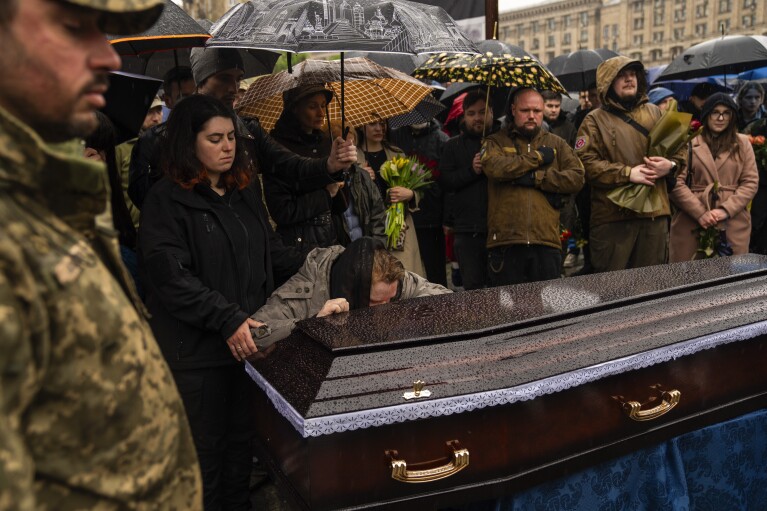 Family, friends and army comrades gather to mourn Ukrainian army paramedic Nazarii Lavrovskyi, 31, killed in the war, during his funeral ceremony at Independence square in Kyiv, Wednesday, April 24, 2024. (AP Photo/Francisco Seco)