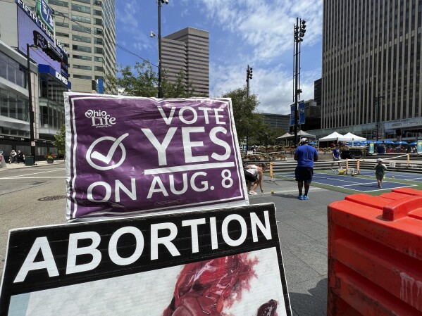 A sign asking Ohioans to vote in support of Issue 1 sits above another sign advocating against abortion rights at an event hosted by Created Equal on Thursday, July 20, 2023, in Cincinnati, Ohio. The fraught politics of abortion have helped turn an August ballot question in Ohio that would make it harder to change the state constitution into a cauldron of misinformation, fear-mongering and vitriol. (AP Photo/Patrick Orsagos)
