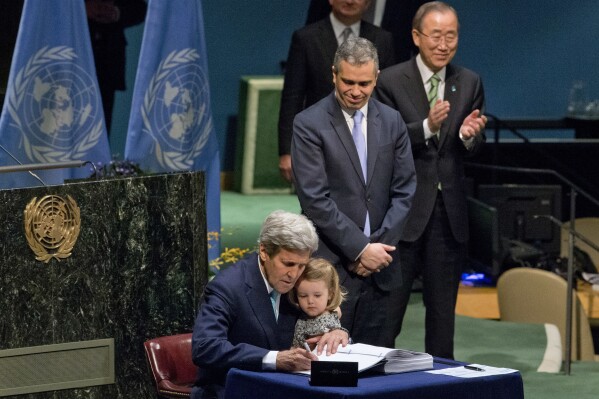FILE - U.S. Secretary of State John Kerry holds his granddaughter as he signs the Paris Agreement on climate change, April 22, 2016 at U.N. headquarters. (AP Photo/Mary Altaffer, File)