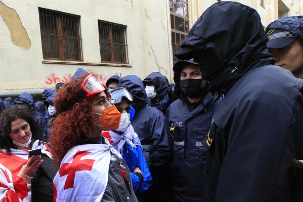 A demonstrator wears a national flag as she argues with the police that blocked the road towards the Parliament building during an opposition protest against 
