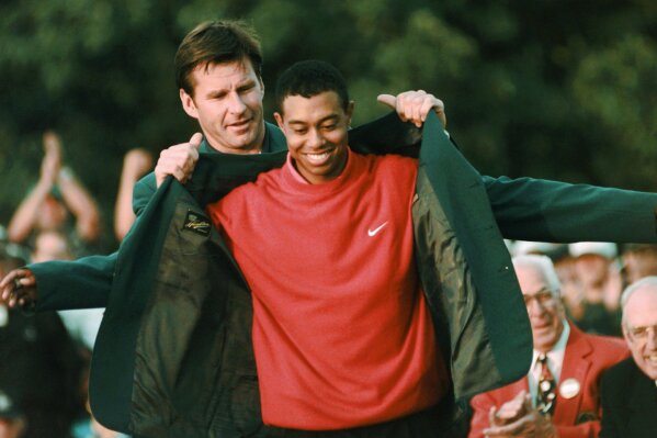 
              FILE - In this April 13, 1997, file photo, Masters champion Tiger Woods receives his Green Jacket from last year's winner Nick Faldo, rear, at the Augusta National Golf Club in Augusta, Ga. Woods completes an amazing journey by winning the 2019 Masters, overcoming 11 years of personal foibles and professional pain that seemed likely to be his lasting legacy. (AP Photo/Dave Martin, File)
            