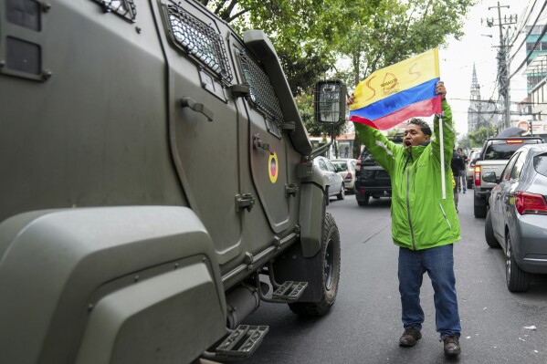 A supporter of Ecuador's former vice president Jorge Glass protests as a military vehicle transports him from the detention center where he is being held after his arrest at the Mexican Embassy in Quito, Ecuador, Saturday, April 6, 2024. Glass, who served as Ecuador's vice president between 2013 and 2018 he was convicted of corruption and had been hiding in the embassy since December.  (AP Photo/Dolores Ochoa)
