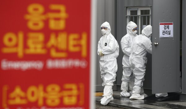 Officials wearing protective attire work to diagnose people with suspected symptoms of the new coronavirus at a hospital in Daegu, South Korea, Wednesday, Feb. 26, 2020. The number of new virus infections in South Korea jumped again Wednesday and the U.S. military reported its first case among its soldiers based in the Asian country, with his case and many others connected to a southeastern city with an illness cluster. A sign reads "Emergency Medical Center." (Kim Hyun-tae/Yonhap via AP)
